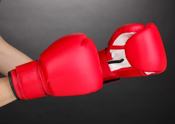 Красные боксерские перчатки на руках на сером фоне — стоковое фото