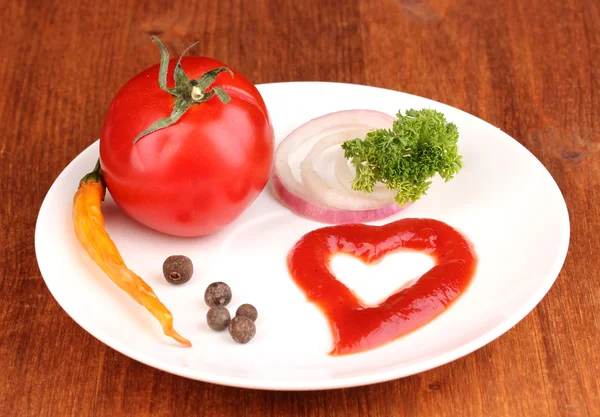 Pomodoro maturo e spezie su piatto su tavolo di legno — Foto Stock