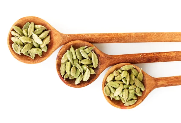 Cardamomo verde in cucchiai di legno su sfondo bianco primo piano — Foto Stock