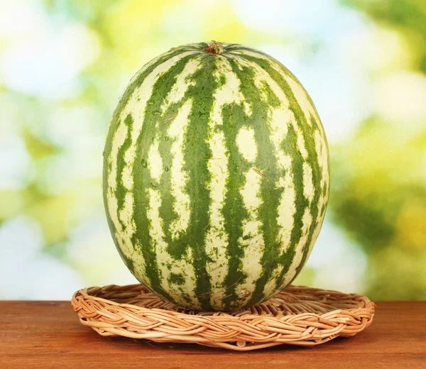 Reife Wassermelone auf Weidenmatte auf grünem Hintergrund Nahaufnahme — Stockfoto