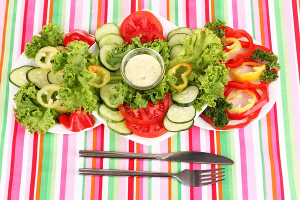 Chopped vegetables and sauce on plate on striped tablecloth — Stock Photo, Image