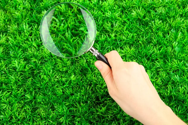 緑の芝生に手で置かれた虫眼鏡 — ストック写真
