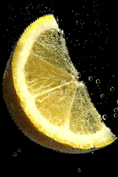 Zitronenscheibe im Wasser mit Blasen, auf schwarzem Hintergrund — Stockfoto