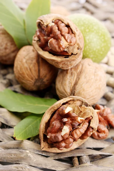 Walnuts with green leaves, on wicker background — Stock Photo, Image