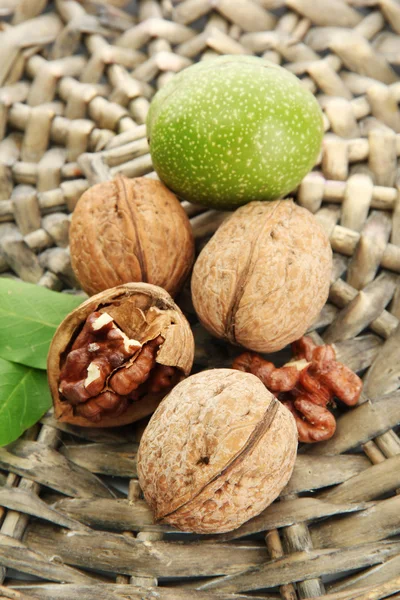 Nueces con hojas verdes, sobre fondo de mimbre —  Fotos de Stock