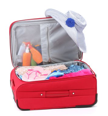 Suitcase with summer clothes, a hat and suntan isolated on white