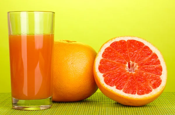 Grapefruit juice and grapefruit on bamboo mat on green background — Stock Photo, Image