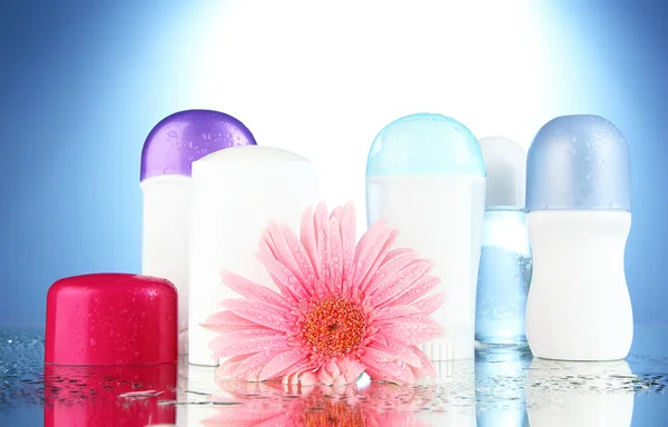 Bottiglie deodoranti con fiore su fondo blu — Foto Stock