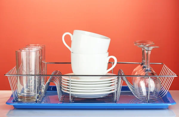 Czyste naczynia na stojak na czerwonym tle — Zdjęcie stockowe