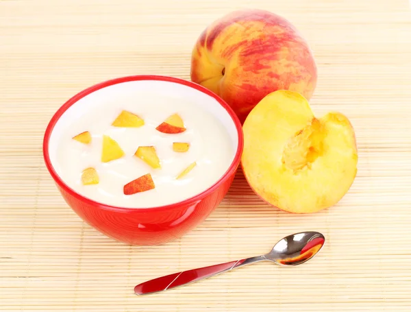 Yogurt con pesca in ciotola su tappetino di bambù — Foto Stock