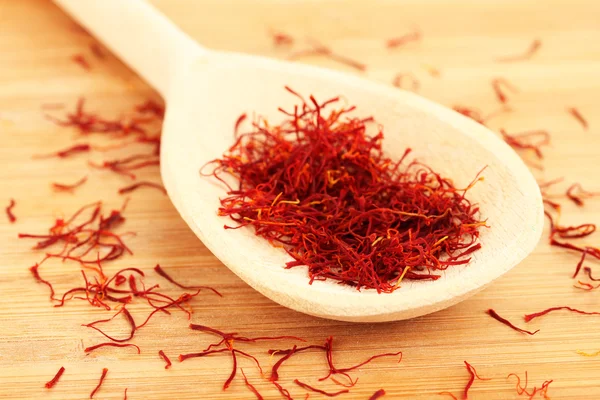 Stigmas of saffron in wooden spoon on wooden background close-up — Stock Photo, Image