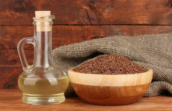 Linseed oil with flax seeds on wooden background close-up — Stock Photo, Image