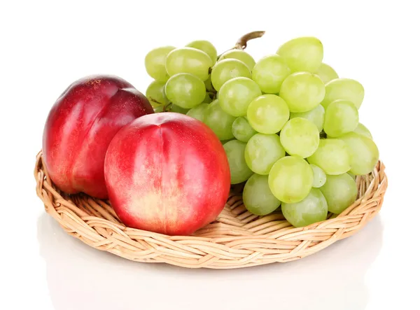 Uvas doces maduras e nectarinas em esteira de vime isolada em branco — Fotografia de Stock