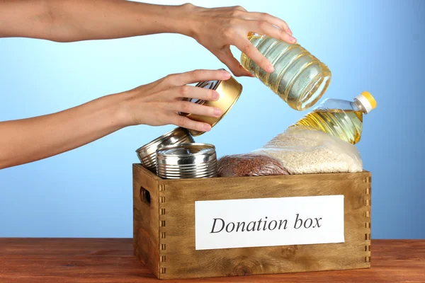 Donation box with food on blue background close-up — Stock Photo, Image