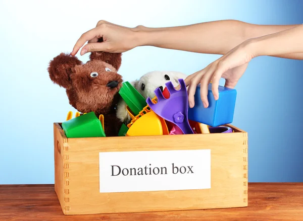 Donatie box met kinderen speelgoed op blauwe achtergrond close-up — Stockfoto