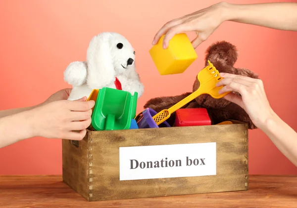 Коробка для пожертвований с детскими игрушками на красном фоне крупным планом — стоковое фото
