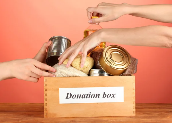 Donation box with food on red background close-up — Stock Photo, Image