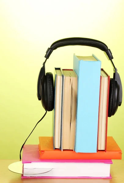 Auriculares en libros sobre mesa de madera sobre fondo verde — Foto de Stock