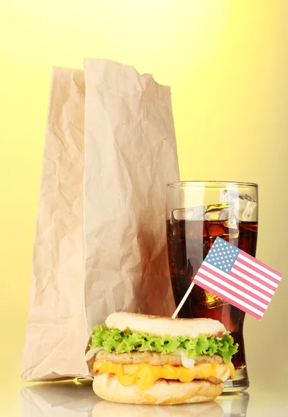 Вкусный сэндвич с американским флагом, колой и упаковкой, на желтом фоне — стоковое фото