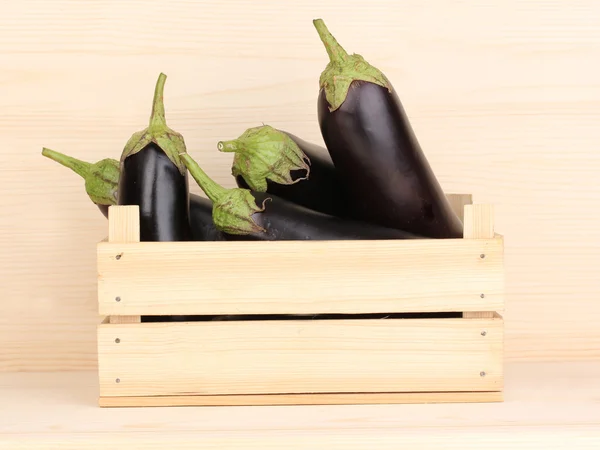 Fresh eggplants in crate on wooden background — Stock Photo, Image