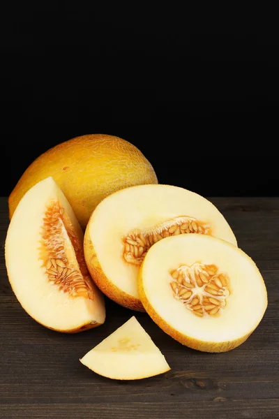 Cortar melones maduros sobre mesa de madera sobre fondo negro —  Fotos de Stock