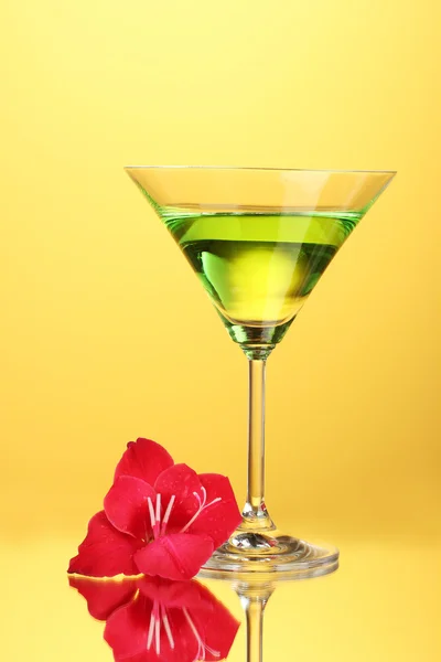 Vaso con cóctel y capullo de gladiolo sobre fondo amarillo —  Fotos de Stock