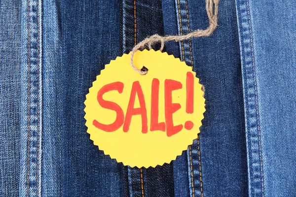 Many jeans with label Sale closeup — Stock Photo, Image