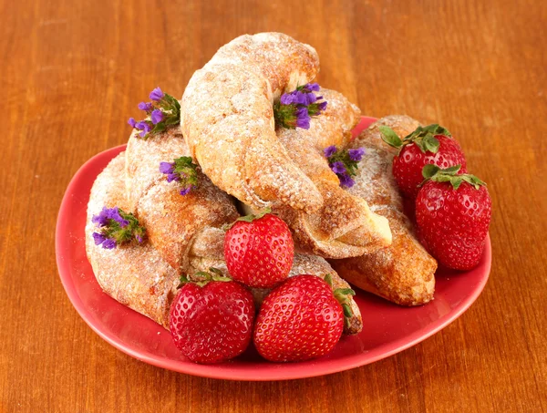 Fresh bagels with strawberry in the plate on wooden background close-up — Stock Photo, Image