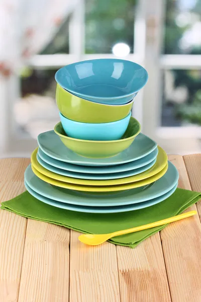 Colorful tableware on wooden table on window background — Stock Photo, Image