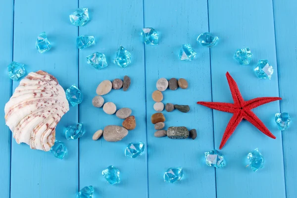 Das Wort Meer und Dekor von Muscheln in Nahaufnahme auf blauem Holztisch — Stockfoto