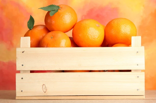 Ripe tasty tangerines with leaves in wooden box on table — Stock Photo, Image