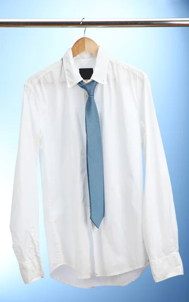 Shirt with tie on wooden hanger on blue background — Stock Photo, Image