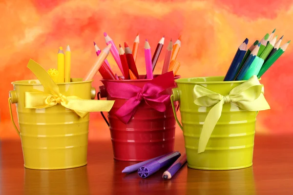 Colorful pencils and felt-tip pens in pails on color background — Stock Photo, Image
