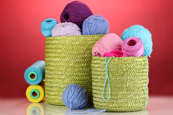 Colorful yarn for knitting in green basket on red background — Stock Photo, Image