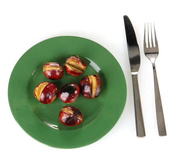 Roasted chestnuts in the green plate with fork and knife isolated on white — Stock Photo, Image