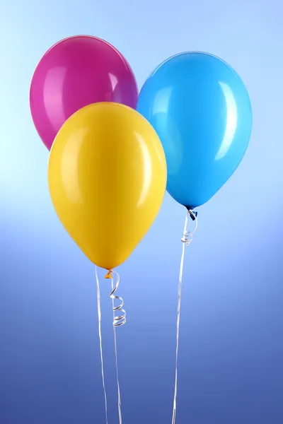 Três balões coloridos em fundo azul — Fotografia de Stock