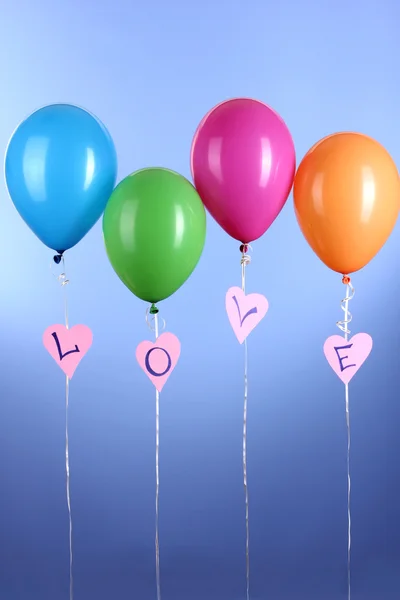 Kleurrijke ballonnen houdt woord liefde op blauwe achtergrond — Stockfoto