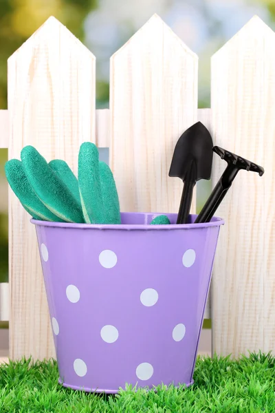 Tuingereedschap op groen gras op houten hek achtergrond — Stockfoto