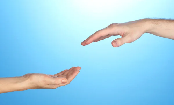 Women's hand goes to the man's hand on blue background Stock Photo