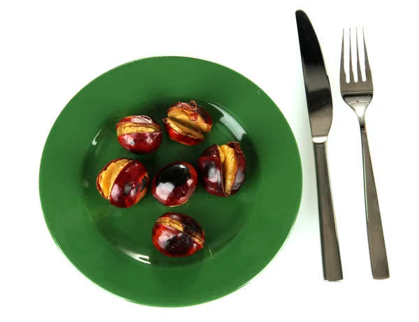 Roasted chestnuts in the green plate with fork and knife isolated on white Royalty Free Stock Images