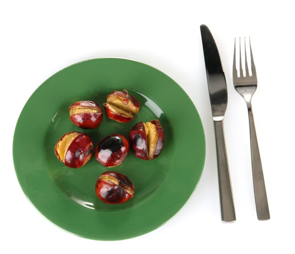 Roasted chestnuts in the green plate with fork and knife isolated on white Stock Image