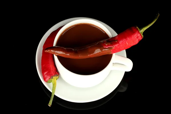 White cup with hot chocolate and chili pepper isolated on black Royalty Free Stock Images