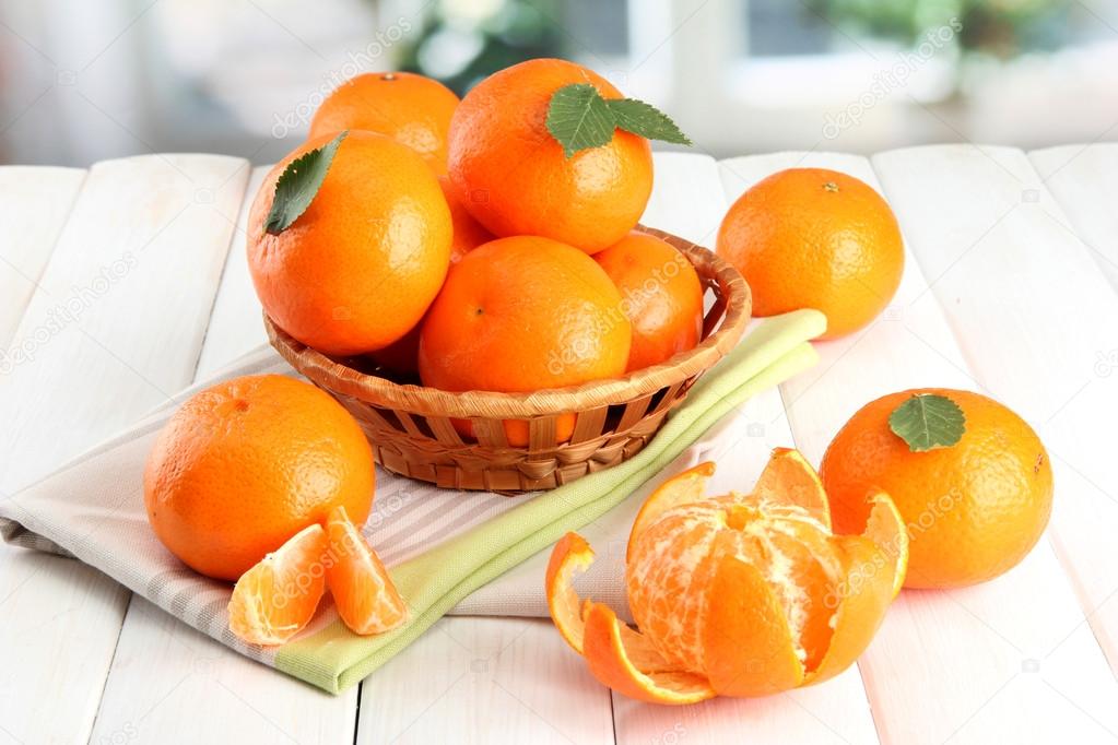 tangerines with leaves in a beautiful basket, on white wooden table