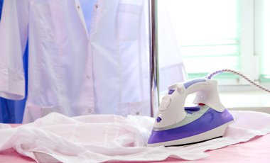 Kumaş arka planda elektrikli ütü ve gömlek.