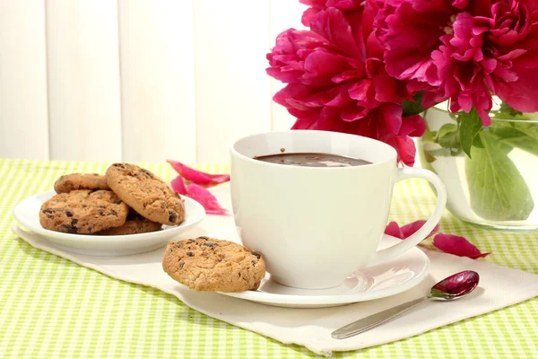 Tazza di cioccolata calda, biscotti e fiori sul tavolo nel caffè — Foto Stock