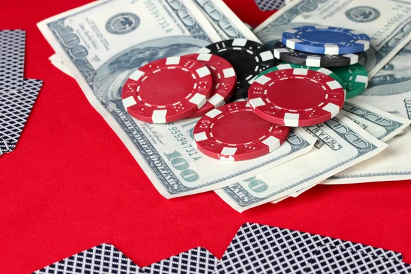 Jouer aux cartes, jetons de poker et dollars sur une table rouge — Photo