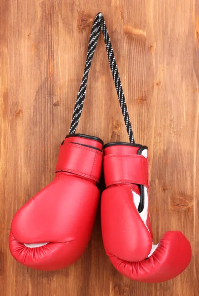 Luvas de boxe vermelho pendurado no fundo de madeira — Fotografia de Stock