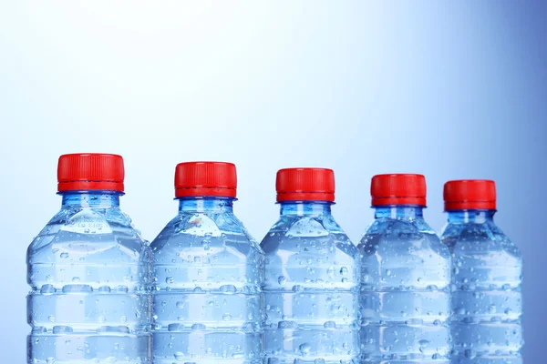 Plastic flessen water op blauwe achtergrond — Stockfoto