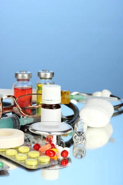 Medicamentos e um estetoscópio em um fundo azul close-up — Fotografia de Stock