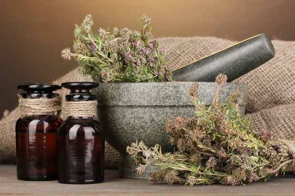 Thyme herb and mortar on wooden table on brown background — Stock Photo, Image